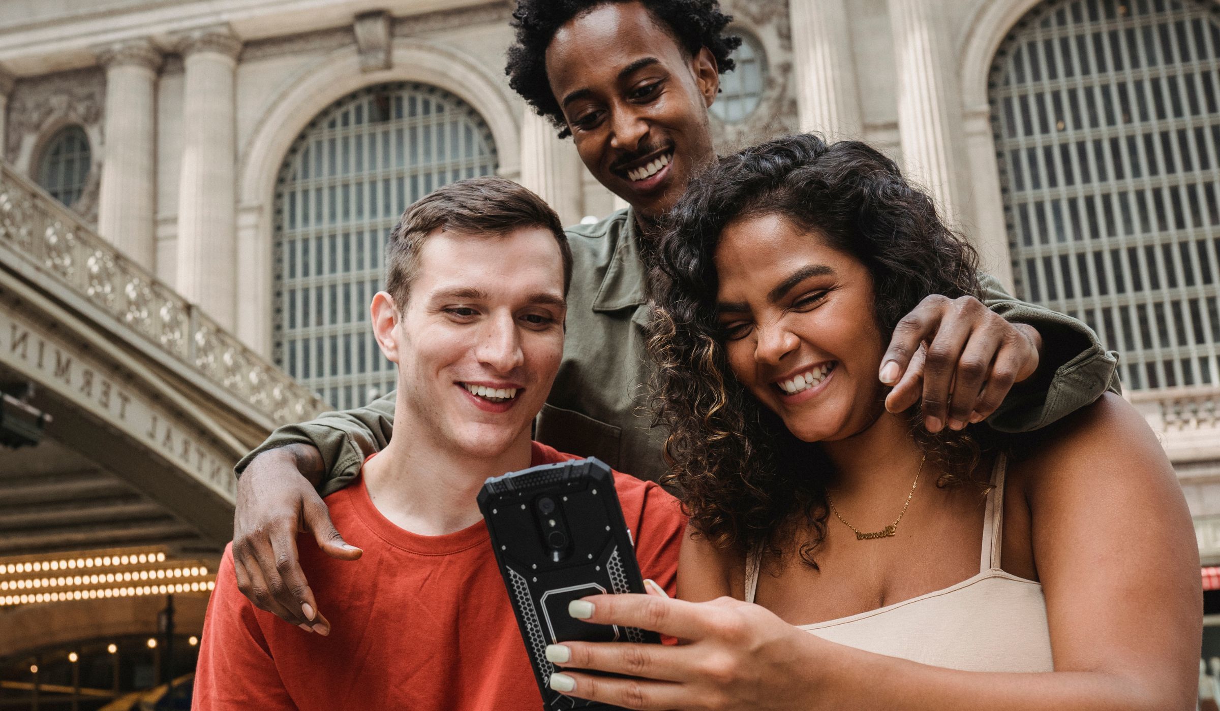 apelidos carinhosos - imagem de um grupo de três amigos olhando um telefone, sorrindo