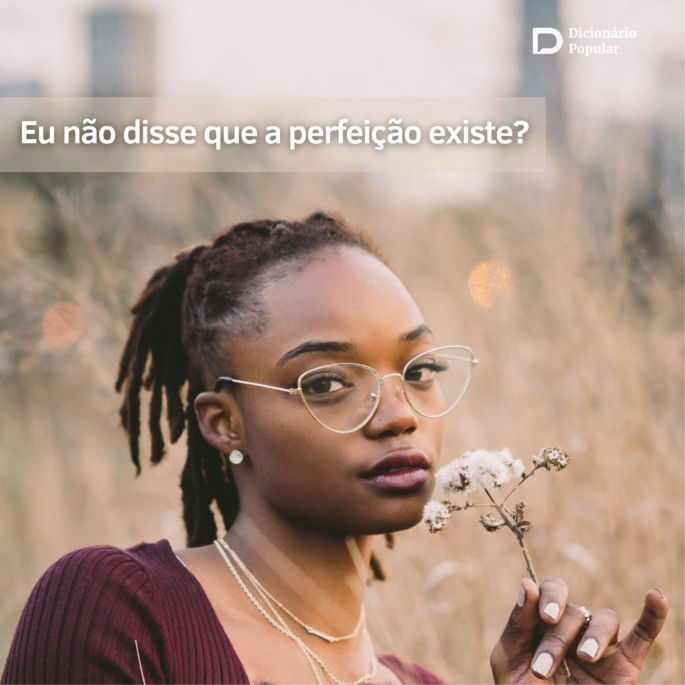 Mulher de óculos segura flor branca e olha para a foto com um fundo de capim
