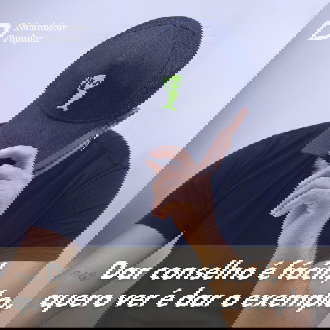 Rapaz esconde o rosto a aba de um boné preto, em frente a uma parede branca