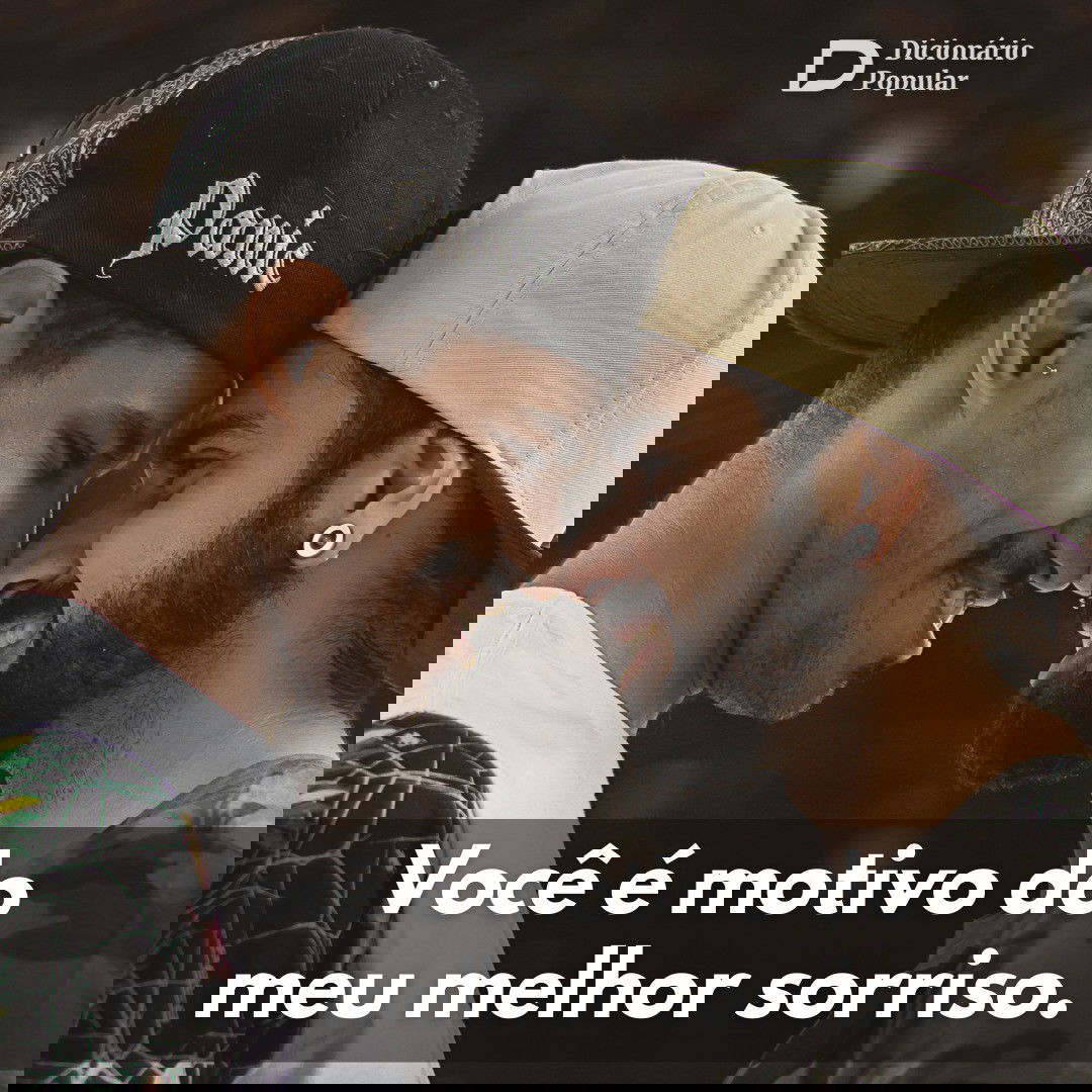 Casal de boné preto e branco se posiciona frente a frente com a testa e nariz encostados e sorriso no rosto