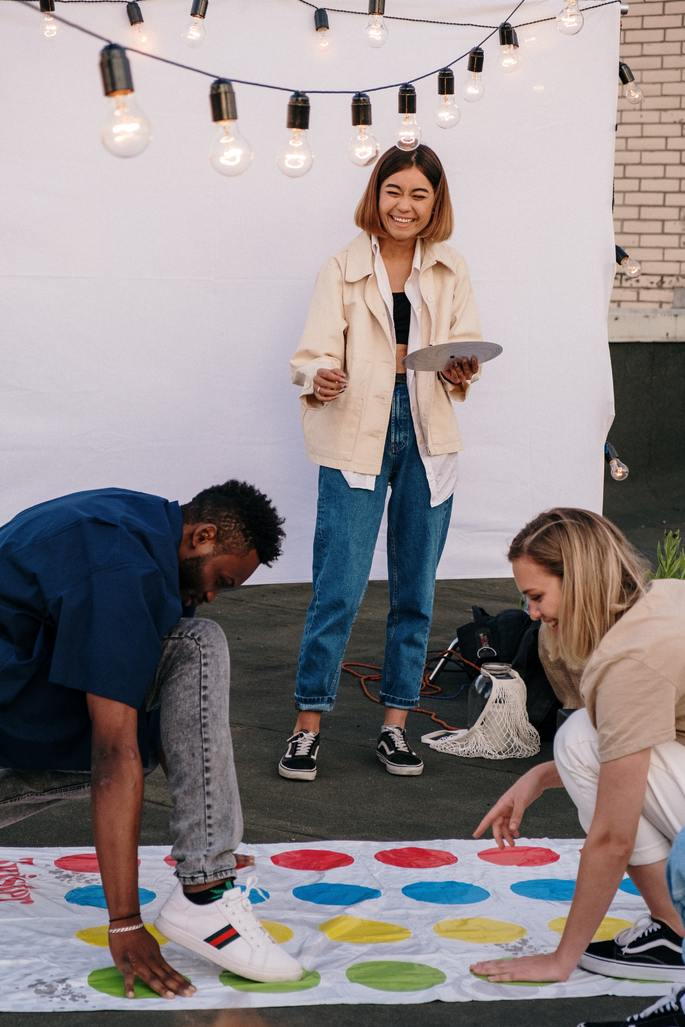 Homem e mulher brincam de Twister e mulher, de pé, gira a roleta
