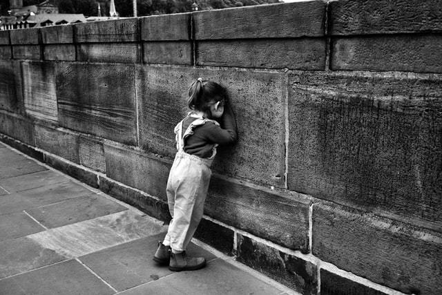 Criança conta encostada na parede em foto em preto e branco